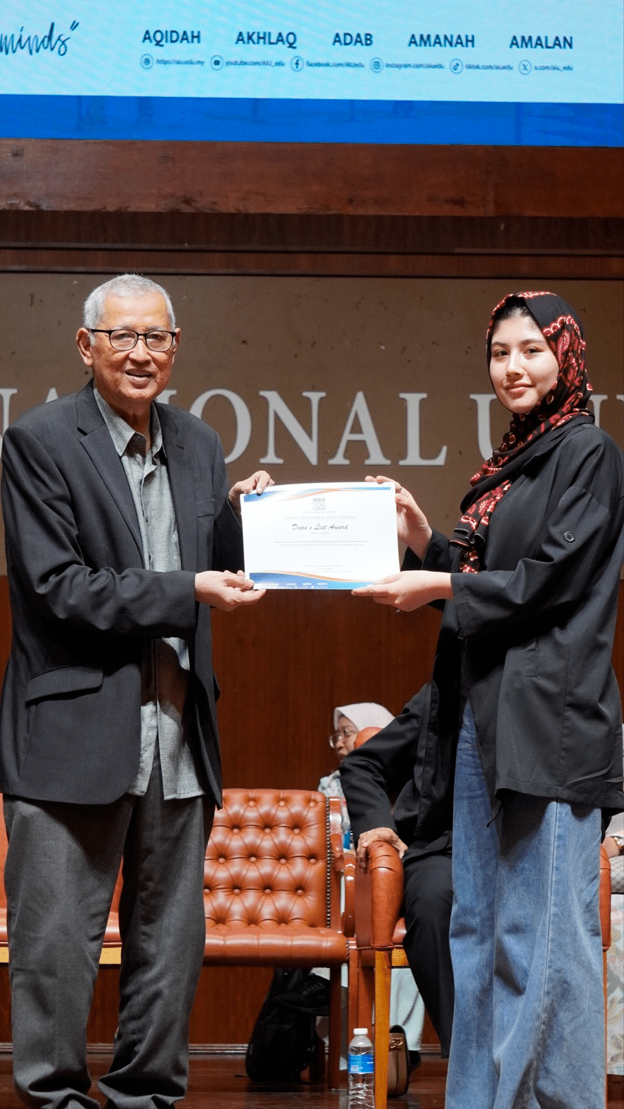 An ASRF student receiving her Dean’s List award certificate from a university official on stage