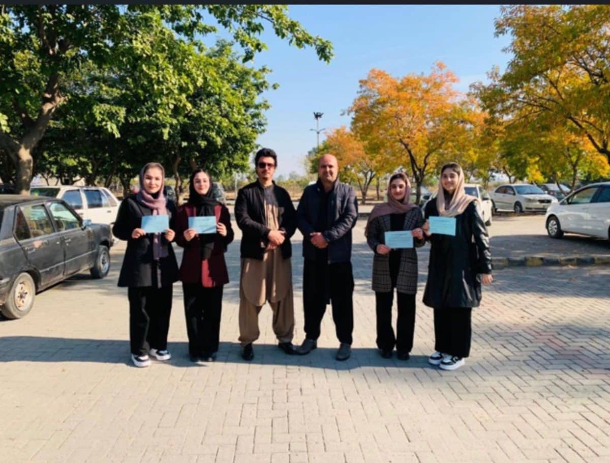 ASRF students and staff standing together on a tree-lined street, holding certificates