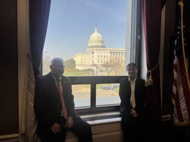 Congressman Sessions and a student sitting on his office windowsill with the Capitol dome behind them