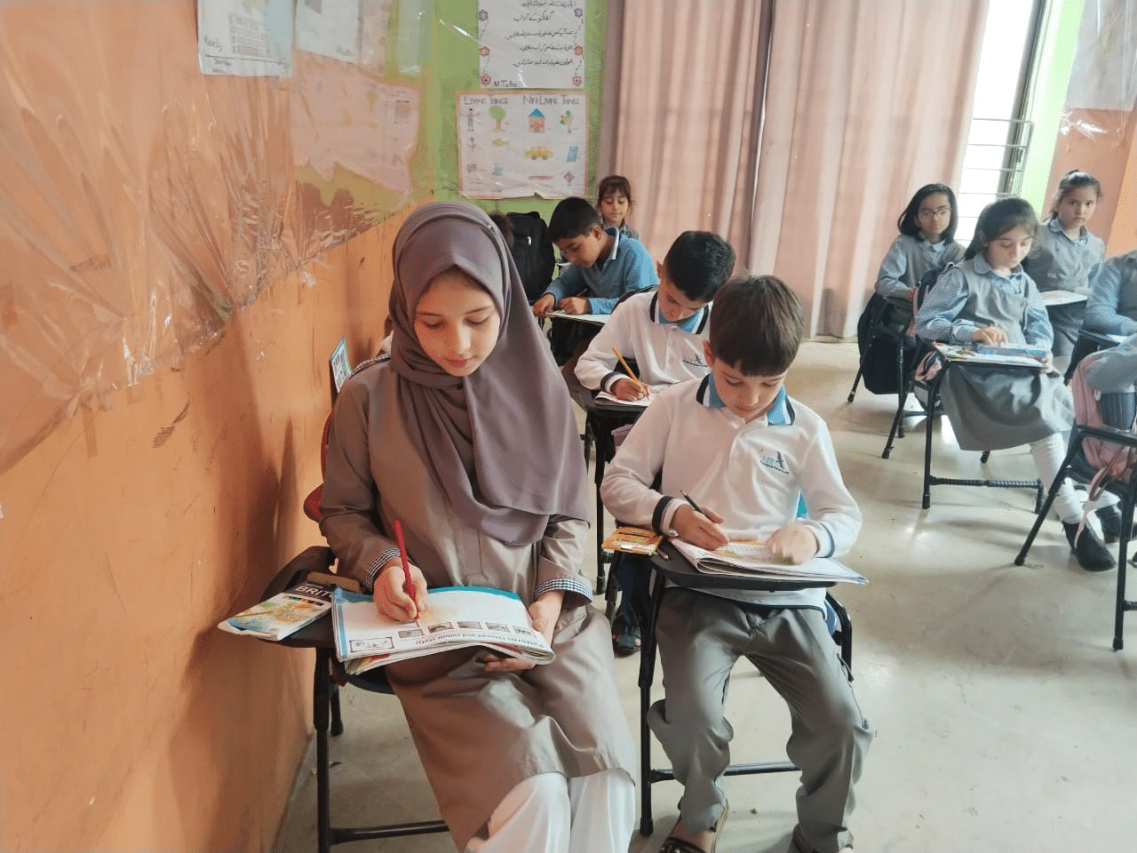 Afghan children writing at their desks in a classroom in Pakistan